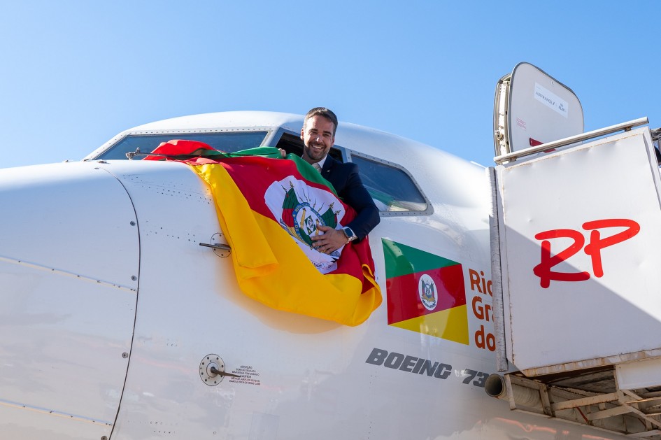 Leite segura uma bandeira do RS na janela da cabine do avião na reabertura do Slagado Filho