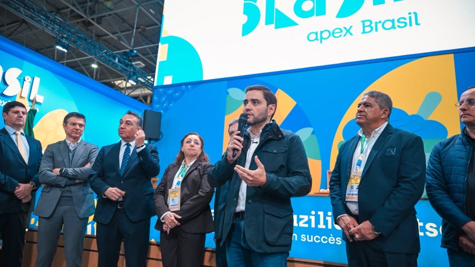 V&aacute;rias pessoas est&atilde;o reunidas em um palco, com uma delas mais ao centro falando ao microfone.