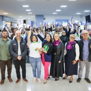 Foto mostra grupo de formandos e autoridades posando todos juntos. Os alunos, ao fundo, levantam os canudos de formatura. Todos parecem estar vibrando com o momento.